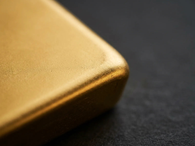 Macro view of the rounded corner and satin surface of a single cast gold bullion bar